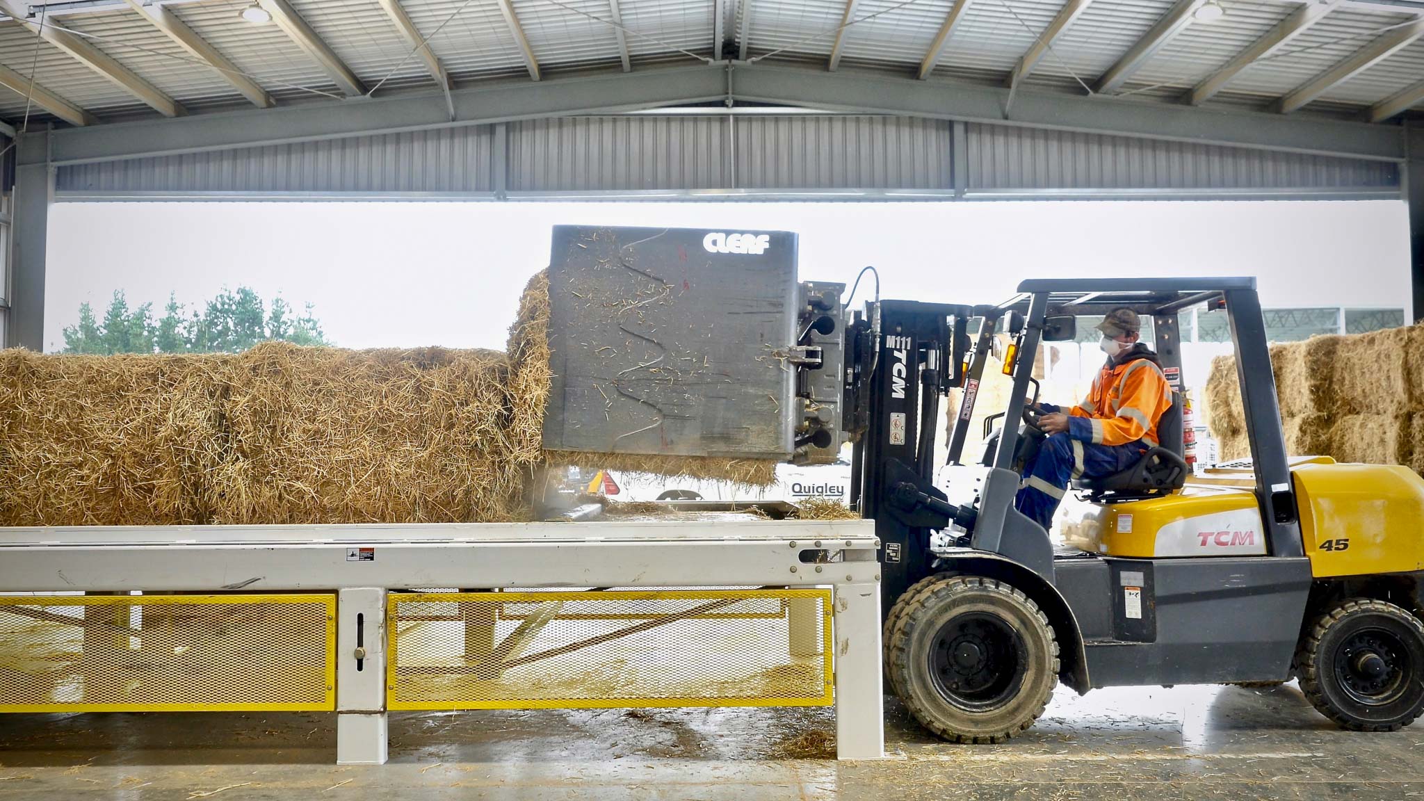 A forklift moving hay in a warehouse.